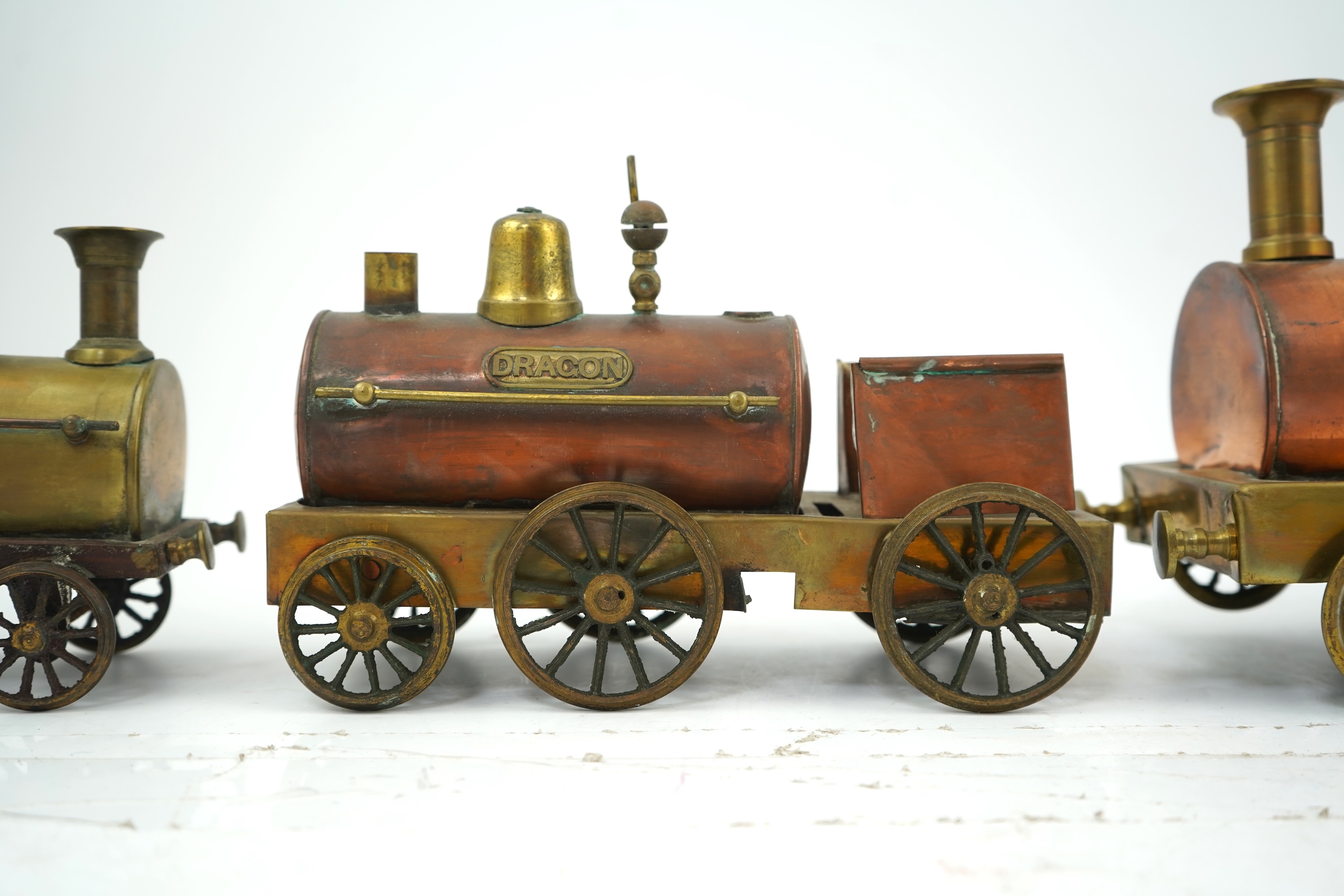 Three late 19th or early 20th century brass and copper live steam locomotives; a 2-2-4, ‘Monarch’, gauged to run on approximately 4 1/2 inch track, 33cm long frames, a 2-2-2, ‘Dragon’, gauged to run on approximately 3 1/